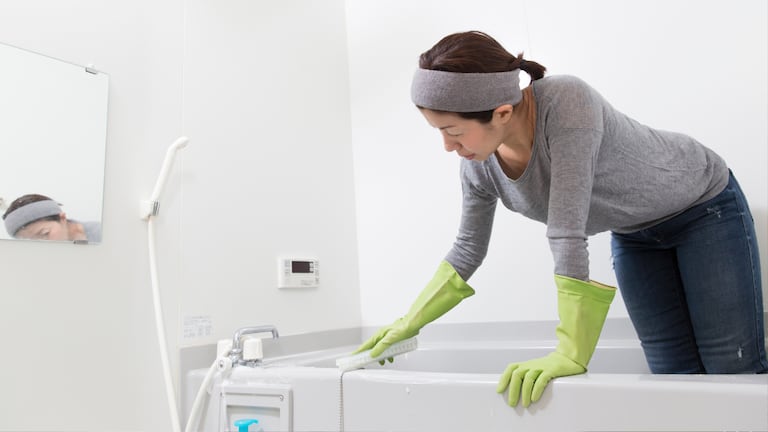 Una mujer limpiando una tina de baño.