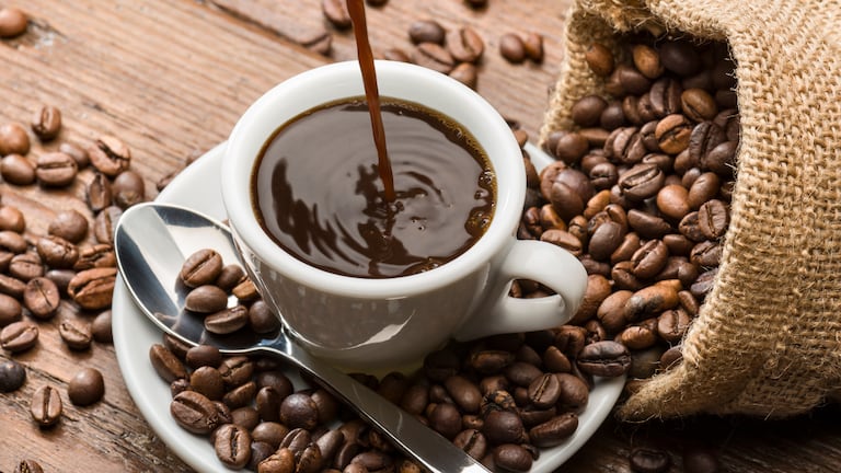 Una rica taza de café y café en grano a un lado.
