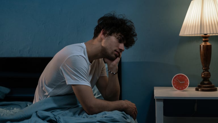 Una persona con insomnio sentado en la cama.