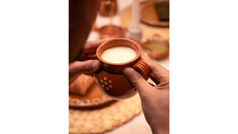 Un mano sosteniendo un taza con atole.