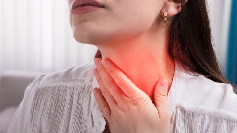Una mujer agarrándose la garganta con indicación de dolor.